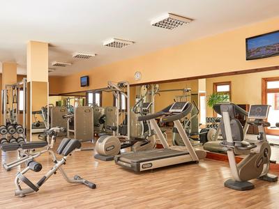 Heller Fitnessraum mit modernen Geräten und Holzboden in einem Hotel.