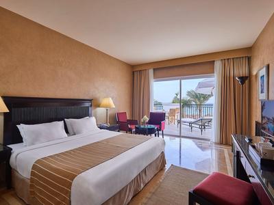 Gemütliches Hotelzimmer mit großem Bett, Schreibtisch und Balkon mit Meerblick.