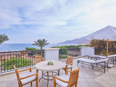 Terrasse mit Sitzbereich und Meerblick, Sonnenschirm und Liegestuhl, palmengesäumt