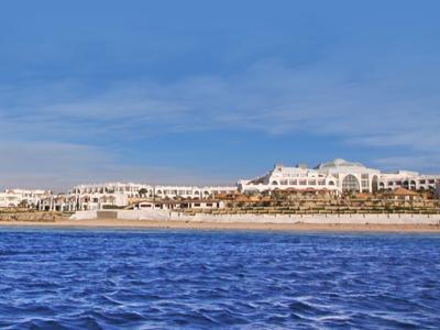 Weitläufiger Strand mit blauem Meer und Hotels entlang der Küste unter hellem Himmel.