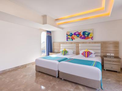 Hell eingerichtetes Hotelzimmer mit zwei Betten, modernem Design und dekorativen Wandbildern.
