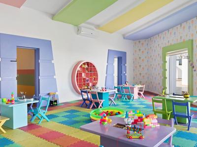 Bunter, heller Spielraum mit Tischen, Stühlen und Spielzeug in einem Hotel für Kinder.