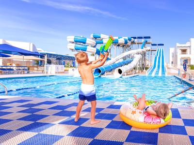Kinder spielen am Pool mit Wasserrutschen in einem sonnigen Hotelresort.