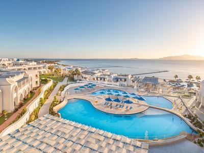Luxuriöses Hotel mit großem Pool und Blick auf das Meer bei klarem Himmel.