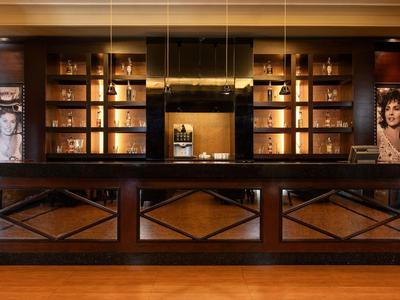 Eleganter Hotellobby-Empfang mit dunklem Holztresen und beleuchteten Regalen im Hintergrund.