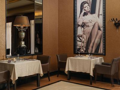 Elegantes Hotelrestaurant mit gedeckten Tischen, bequemen Stühlen und stilvoller Wanddekoration.
