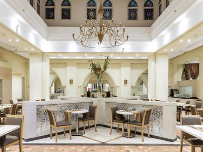 Elegantes Hotelrestaurant mit hellem Interieur, modernen Möbeln und zentralem Blumenarrangement.
