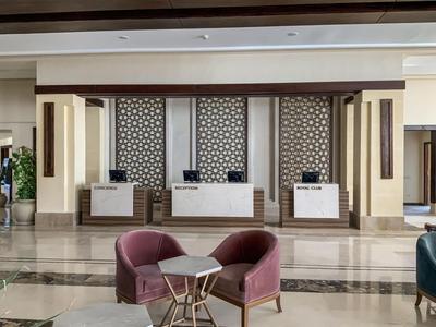 Eleganter Hotel-Empfang mit drei Tresen und bequemen Stühlen im Vordergrund.
