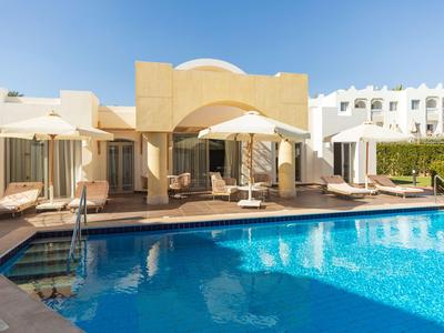 Moderner Hotelpool mit Sonnenliegen und Sonnenschirmen unter klarem blauem Himmel.