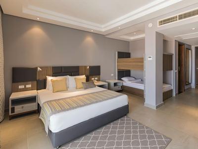 Modern eingerichtetes Hotelzimmer mit Doppelbett, Etagenbett und neutralen Farbtönen.