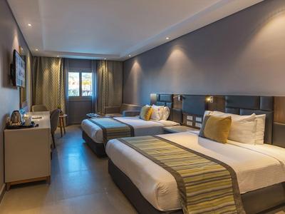 Modern eingerichtetes Hotelzimmer mit zwei Einzelbetten, Nachtlichtern und Schreibtisch.