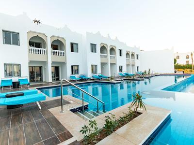 Moderner Hotelkomplex mit weißer Fassade und großem, klarem Außenpool.