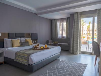 Modernes Hotelzimmer mit Doppelbett, Balkon und gemütlicher Sitzgruppe.