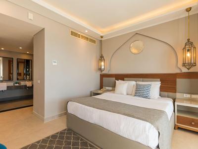 Modernes Hotelzimmer mit Doppelbett, indirekter Beleuchtung und Zugang zu einem Badezimmer.