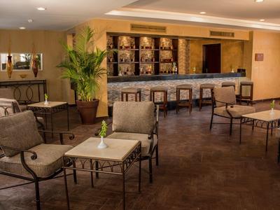 Innenraum einer Hotelbar mit Sitzgelegenheiten und Theke in warmem Licht.