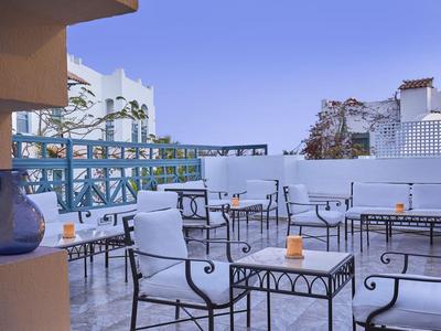 Terrasse mit weißen Stühlen und Tischen aus Schmiedeeisen mit blauem Himmel im Hintergrund in einem Hotel.