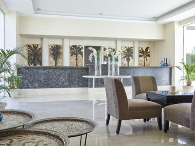 Modernes Hotelinterieur mit Stehtisch, bequemen Stühlen und dekorativen Pflanzen.