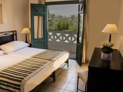 Gemütliches Hotelzimmer mit Doppelbett, offenem Balkon und Blick auf grüne Landschaft.