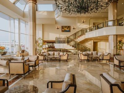 Elegante hall dell'hotel con poltrone comode, grandi finestre e scala curva.