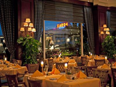 Ristorante elegante con tavoli apparecchiati, tovaglie gialle e vista su un'insegna dell'hotel illuminata.