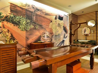 Holzinterieur mit einem großen Holztrog, Pflanzen und dekorativen Gegenständen in einem Hotelzimmer.