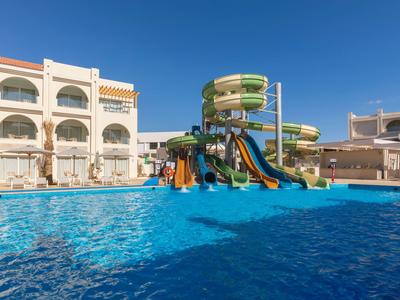 Wasserpark mit Rutschen und Pool, umgeben von Hotelgebäuden unter klarem Himmel.