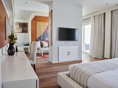 Modernes Hotelzimmer mit Doppelbett, Flachbildfernseher, Vorhängen und hellem Interieur.