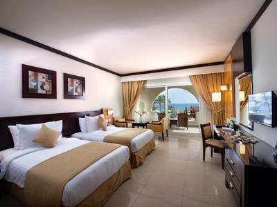 Heller Hotelzimmer mit zwei Einzelbetten, Balkon und Blick auf den Pool
