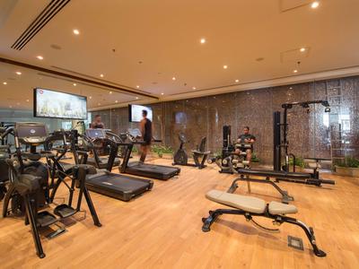 Modernes Fitnessstudio mit verschiedenen Trainingsgeräten und hellem Holzboden in einem Hotel.