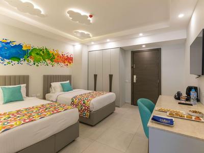 Modernes Hotelzimmer mit zwei Einzelbetten, bunten Akzenten und einem Schreibtisch mit Stuhl.