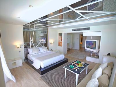 Modernes Hotelzimmer mit großem Bett, Sofa und Glaswand zum Badezimmer.