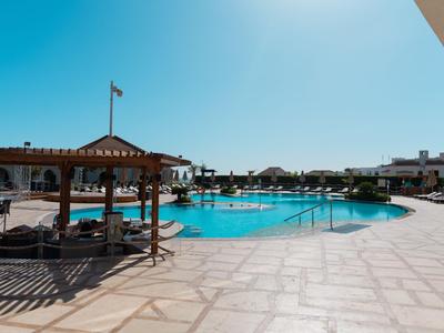 Großer Poolbereich mit Sonnenschirmen und Liegen in einem Hotel bei klarem Himmel.