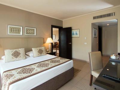 Modern eingerichtetes Hotelzimmer mit großem Bett, Schreibtisch und warmen Beleuchtung.