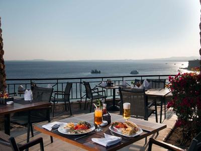 Terrasse mit gedeckten Tischen und Meerblick bei Sonnenuntergang im Hotel.