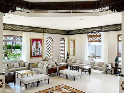 Heller, luxuriöser Hotellobby mit Sofas, Hockern und großen Fenstern mit Blick auf Garten.