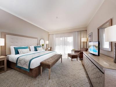 Modern eingerichtetes Hotelzimmer mit großem Bett und Zugang zu einem Balkon.