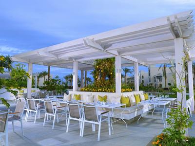 Modernes, offenes Terrassenrestaurant mit weißen Möbeln und grüner Dekoration bei Tageslicht.