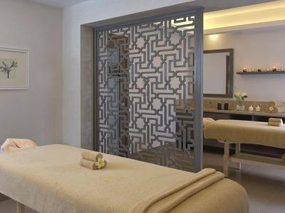 Heller Wellnessraum mit Massageliegen, sanften Farben und dekorativem Raumteiler.