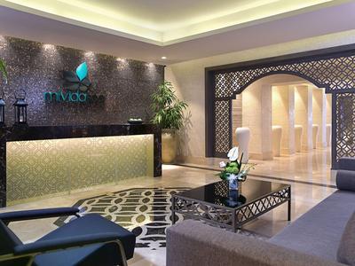 Elegante Hotellobby mit modernem Empfangstresen, gemütlicher Sitzecke und dekorativem Teppich.