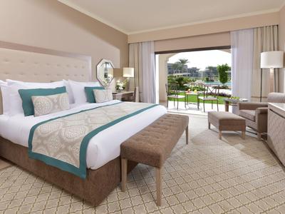 Modernes Hotelzimmer mit großem Bett, Sitzbereich und Blick auf einen Garten.
