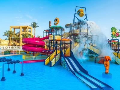 Wasserpark mit bunten Wasserrutschen und spritzenden Wasserfontänen bei sonnigem Himmel.