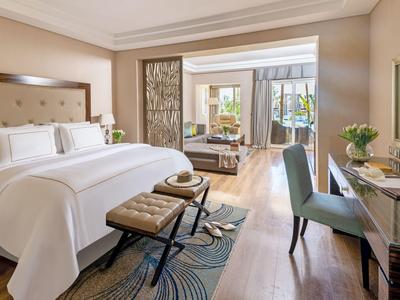 Elegantes Hotelzimmer mit großem Bett, Schreibtisch und Sitzecke, warm beleuchtet und modern eingerichtet.