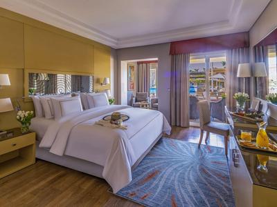 Hell eingerichtetes Hotelzimmer mit großem Bett und Balkon mit Meerblick.