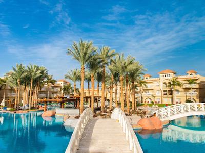 Luxushotel mit Pool und Palmen unter blauem Himmel.