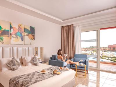 Moderner Hotelraum mit Doppelbett, Sitzbereich und Balkon mit Ausblick.