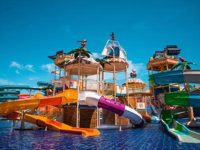 Buntes Wasserparkgebäude mit mehreren Wasserrutschen und einem großen Wasserbecken darunter.