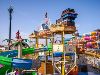Bunter Wasserspielplatz mit Rutschen und Strukturen unter blauem Himmel in einem Ferienresort.