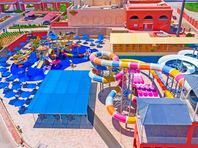 Buntes Wasserparkgelände mit Wasserrutschen, Schwimmbecken und Sonnenschirmen neben Hotels.