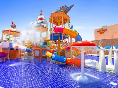 Farbenfroher Wasserpark mit Rutschen, Wasserspielen und blauer Kacheloberfläche im Hotel.