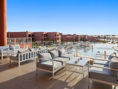 Moderne Terrassenmöbel auf einem Balkon mit Blick auf Hotelgebäude und Pool unter klarem Himmel.